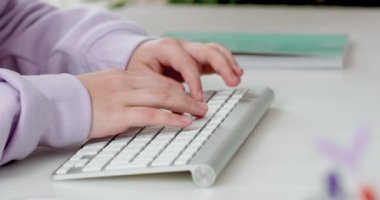 Genç kız klavyede yazıyor ve fareyi kullanıyor, bilgisayarla çalışıyor..
