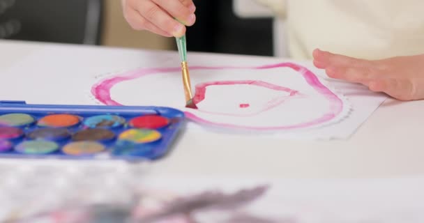 Close-up van een klein meisje gezicht, die is het tekenen van aquarellen. — Stockvideo