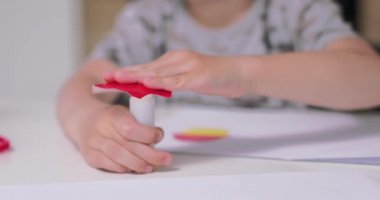 Küçük çocukların ellerini kapayın, kağıt nesnesinden kesilen kağıda yapıştırıcı sürün, renkli kağıt ve yapıştırıcıyla uygulamalar yaparken, mutfakta masada otururken