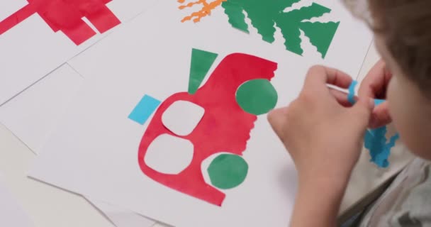 Закройте руки маленьким мальчикам, которые наклеивают цветные бумажные части приложения на — стоковое видео