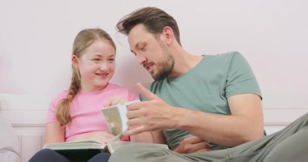 父親の終わりと笑いの十代の娘はソファに座って、写真アルバムを見て. — ストック動画