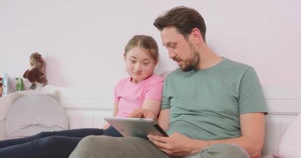 Pai e filha adolescente sentados no sofá na sala de estar, navegando na loja on-line, desfrutando fim de semana Pai pergunta o que ela pensa sobre alguns dos artigos — Vídeo de Stock