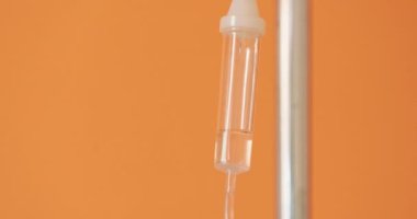 Veteriner kliniğindeki damar içi damlatma aplikatörü, kısmen sıvı ilaçla dolu, arka planda Turuncu duvarların içine düşüyor.