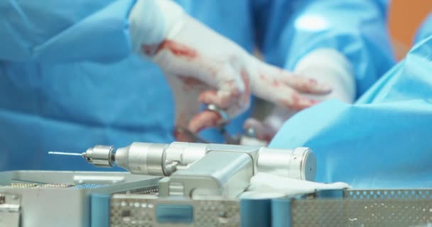 Perceuse chirurgicale concentrée sur les récipients de stérilisation avec des outils stérilisés Mains floues du vétérinaire masculin, en gants blancs et en tenue chirurgicale, alors qu'il opère la jambe arrière d'un — Video