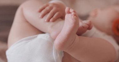 Güzel, uyuyan bir bebeğin ayaklarını kapat, çıplak, bezli, emzik ile, yatakta.