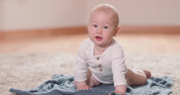 Närbild av liten baby krypa på mattan och filt på golvet, stiger på alla fyra vita väggen på bakgrunden — Stockvideo