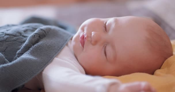 Gros plan d'un beau bébé endormi sous la couverture grise, qui détourne la tête de la caméra — Video