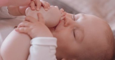 Uyurken, çıplak, bezli, yatakta parmaklarını yalayan sevimli uyuyan bebeği kapat.