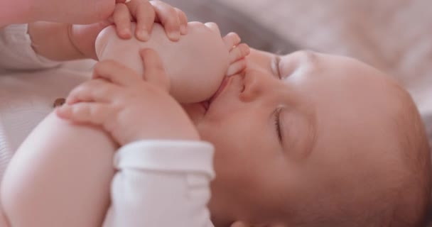 Bezár aranyos alvó baba, aki szopja az ujját lábon, miközben alszik, meztelenül, pelenkában, az ágyban — Stock videók