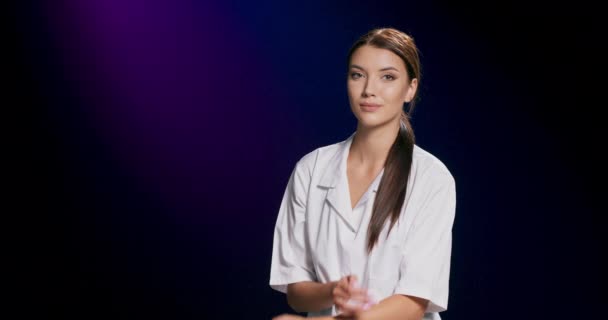 Ein brünettes Model in weißer Bluse lächelt in die Kamera, während es vor dunkelviolettem Studiokulisse mit Kopierraum posiert — Stockvideo