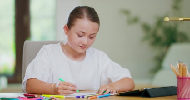 Close-up focado sorrindo menina adolescente, na mesa, desenha com canetas de feltro verde na folha de papel branco e olha para tablet na frente dela na mesa Primeiro plano e fundo são borrados — Vídeo de Stock