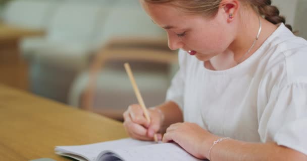 책상에 누워 있는 집중하고 있는 10 대 소녀는 워크 북에서 과제를 수행하고 노트북 백 그라운드에서 그것들을 확인합니다. — 비디오