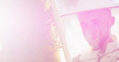 Arı kovanı çerçevesi, bir sürü başıboş arı, bal peteği, balmumu ve bal, beyaz koruyucu takım elbiseli genç bir erkek arı yetiştiricisi tarafından tutuluyor, o incelerken kamera sağa gidiyor.