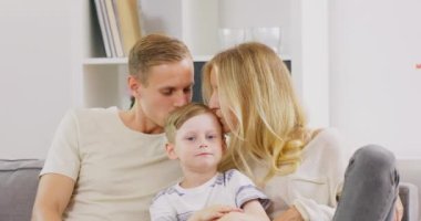 Mutlu genç baba ve anne çift, çocuklarını evde kafalarından öpüyor.