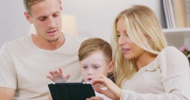 Mutlu Polonyalı aile evde aletle eğleniyor, beyaz aile ve çocuk dijital tablet kullanıyor kanepede birlikte oturuyor, şirin çocuk bilgisayarlı çizgi film seyrediyor.