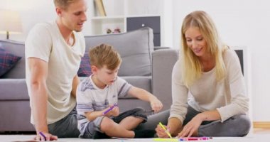 Yerde oturan sevimli küçük çocuk aile aktiviteleriyle meşgul. Albümde genç ebeveynlerle birlikte boya, mutlu anne ve baba rahatla. Küçük oğlunla vakit geçir.