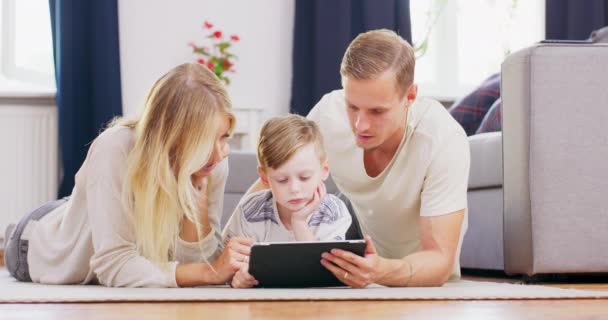 Piękni młodzi rodzice i ich uroczy synek używają tabletu cyfrowego i uśmiechają się, spędzając razem czas — Wideo stockowe