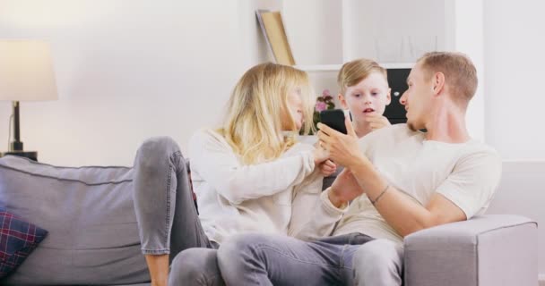 Boldog lengyel család szórakozás készülék otthon, kaukázusi szülők és kisgyerek fiú segítségével digitális tabletta nézi a képernyőn ülni a kanapén együtt, aranyos gyerek tartsa pc nevetés nézni rajzfilmek online — Stock videók