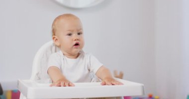 Beyaz bebek sandalyesinde küçük bir bebeğin portresi Arka planda beyaz duvarlar