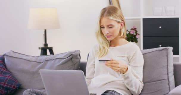 Geconcentreerde vrouw zitten op gezellige bank thuis met laptop op knieën surfen op internet, gelukkig meisje brengen weekend in appartement ontspannen op de bank en online winkelen — Stockvideo
