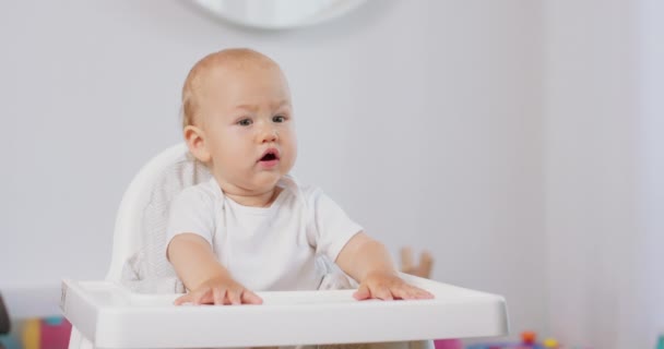 Portrét malého dítěte v bílé vysoké dětské křeslo Bílé stěny na pozadí — Stock video