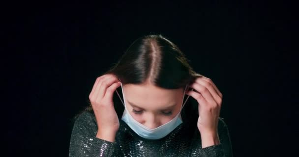 Крупним планом на обличчі жінки в захисній медичній масці для обличчя, дивлячись на камеру Тисячолітня дівчина дивиться на камеру — стокове відео