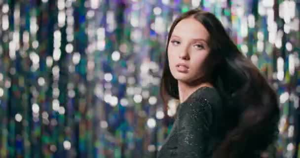 Close-up de uma garota morena que fica de costas para a câmera e depois se vira em câmera lenta, seu cabelo soprando, ela olha para a câmera e sorri um pouco — Vídeo de Stock