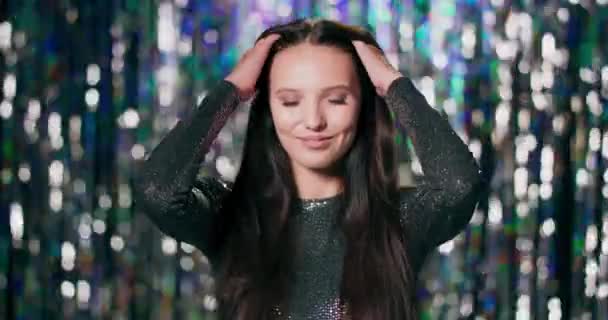 Retrato de belleza de una mujer caucásica con hermoso pelo largo mirando a la cámara contra un fondo de cortinas de plata brillante estudio — Vídeo de stock