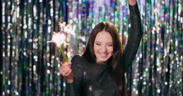 Χαρούμενη γυναίκα κρατώντας sparklers στο κόμμα Teenage κορίτσι απολαμβάνοντας την παραμονή της Πρωτοχρονιάς με πυροτεχνήματα Εορτασμός, bachelorette κόμμα, γενέθλια, χειμερινές διακοπές Υπάρχει ένα λαμπερό φόντο κουρτίνες — Αρχείο Βίντεο