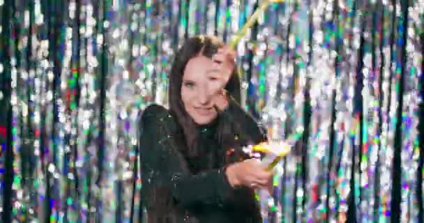 Cheerful woman holding sparklers at the party Teenage girl enjoying new years eve with fireworks Celebration, bachelorette party, birthday, winter holidays There is a shiny curtains background — Stock Video