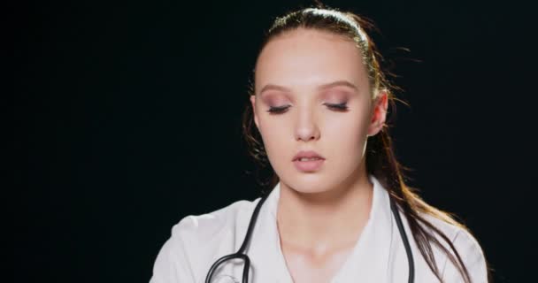 Portrait of a worried and sad young female doctor against a black studio background with copy space — Stok Video