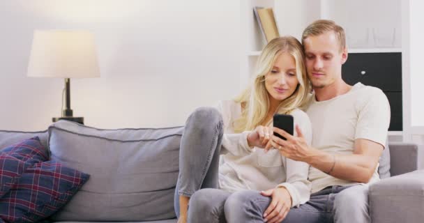 De beaux jeunes parents utilisent une tablette numérique et sourient tout en passant du temps ensemble — Video