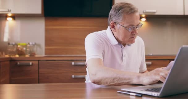 Warm getöntes Porträt eines älteren Mannes, der online einkauft oder mit Kreditkarte Steuern zahlt, während er zu Hause Laptop benutzt, Kopierplatz — Stockvideo