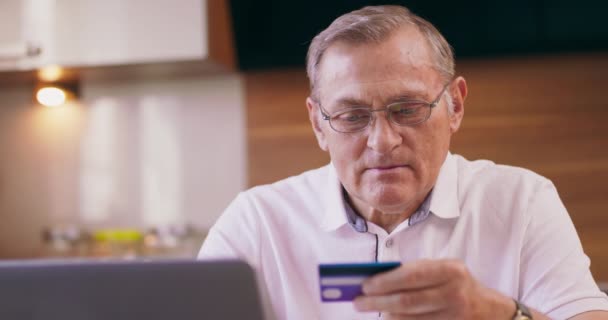Portret skoncentrowanego starszego mężczyzny dokonującego płatności online rachunku za pomocą laptopa Uśmiechnięta dojrzała kobieta robi zakupy online Emeryt korzystając z laptopa do bankowości internetowej — Wideo stockowe