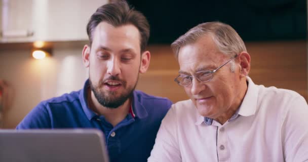 Syn pomaga ojcu wprowadzić numer karty kredytowej do laptopa w domu, aby dokonać płatności rachunków online — Wideo stockowe