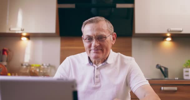 Szczęśliwy siwowłosy dojrzały mężczyzna w okularach krzyczy, świętuje sukces, wygrana online, udany zakład, za pomocą laptopa, siedzi na krześle w kuchni, patrząc na ekran — Wideo stockowe