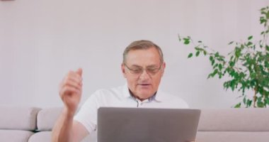 Dizüstü bilgisayarı olan yaşlı bir adam iyi haberleri okuduğu için seviniyor.