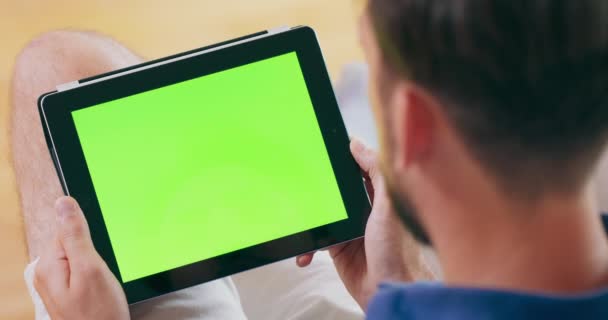 Um homem recebe uma chamada de vídeo em um computador tablet, que possui uma tela verde — Vídeo de Stock