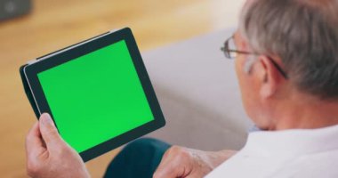 Büyükbaba yeşil ekranlı bir tablet bilgisayar kullanır.