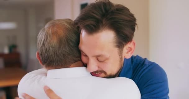 Een glimlachende jongeman knuffelt zijn oudere vader thuis — Stockvideo