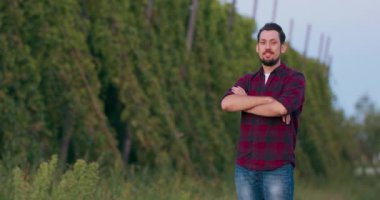 Bira yapmak için şerbetçiotu tarlasında duran gülümseyen bir erkek çiftçinin portresi