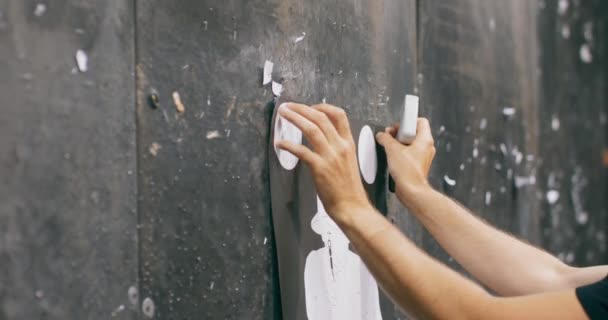 Close-up op de handen van een man nieten een schietbaan doel aan een muur — Stockvideo