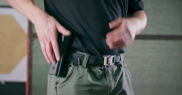Detailní záběr instruktora střelby, jak vytahuje pistoli z pouzdra na střelnici — Stock video