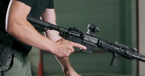 Een man laadt een magazijnclip op een geweer en vuurt een kogel af op een indoor schietbaan. — Stockvideo