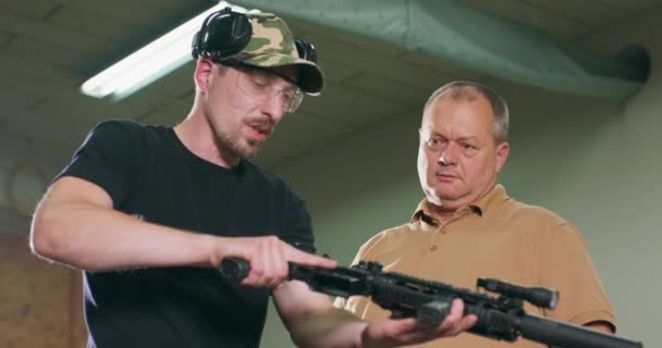 Een man leert schieten op de schietbaan. — Stockvideo