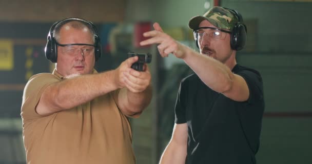 射撃場で銃を撃つ方法を学ぶ男 — ストック動画