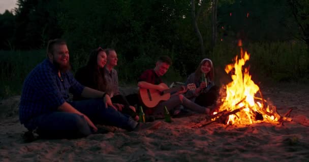 Grupa młodych ludzi śpiewa wokół ogniska na świeżym powietrzu — Wideo stockowe