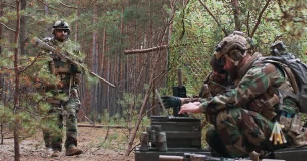 Des soldats barbus en uniforme militaire des bois reviennent d'une reconnaissance vers une base temporaire dans la forêt Au premier plan, vous pouvez voir le commandant travailler sur un ordinateur portable — Video