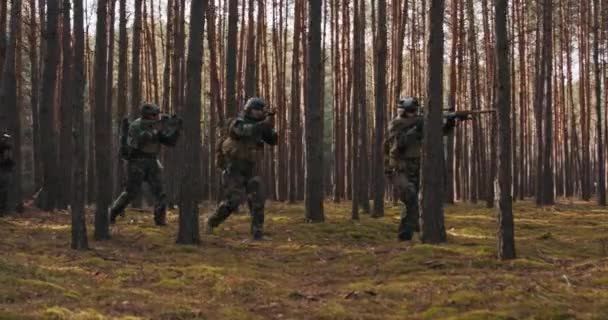 Une escouade de quatre soldats entièrement équipés en camouflage dans le cadre d'une mission militaire de reconnaissance visant les fusils Ils se déplacent en formation à travers la forêt dense — Video