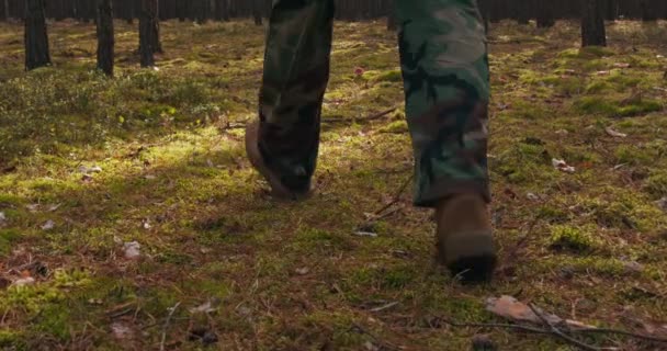 Nahaufnahme eines Militärschuhs, der mittags in Formation durch dichten Wald auf dem herbstlichen Unterholz spaziert — Stockvideo